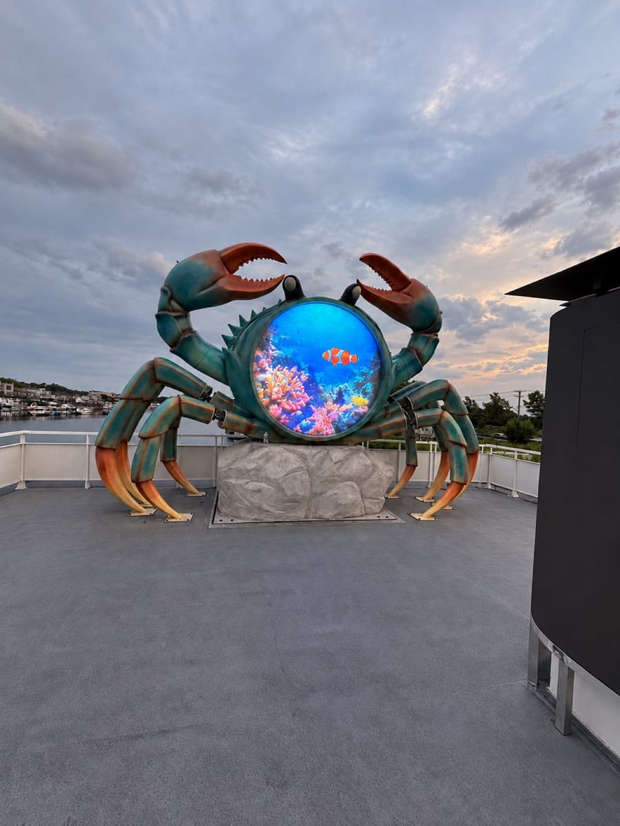 Custom circular LED screen built into a crab sculpture on an outdoor waterfront deck